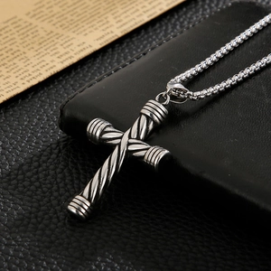 Dettaglio della croce in acciaio inossidabile argento con trama a righe su una collana