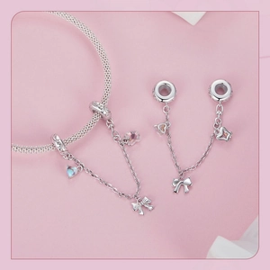 Detail of silver bow and star charms on a safety chain for DIY beaded bracelets