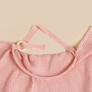 Detailed macro shot of pink waffle cotton nursing cover fabric with natural wooden ring