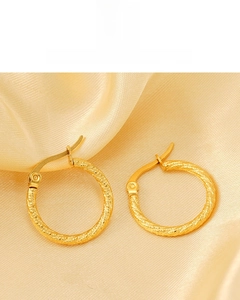 Detail shot of 18K gold plated twisted hoop earrings on luxury silk background