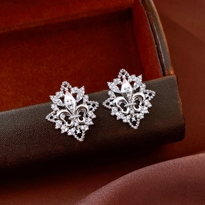 Close-up of silver fleur-de-lis earrings with cubic zirconia on premium leather box
