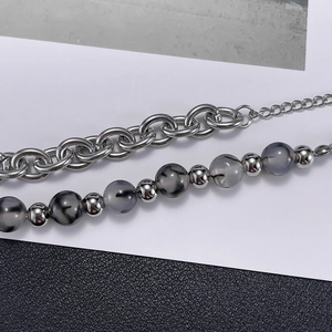 Detail of a double-layer stainless steel bracelet featuring grey and black patterned beads