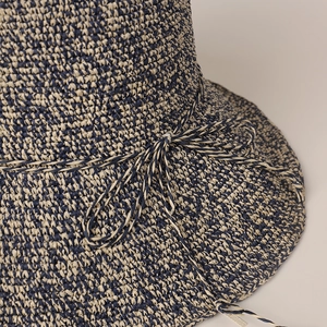 Gros plan d'un chapeau de paille à texture tissée bleu marine et beige avec nœud décoratif