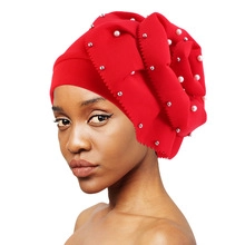 Detail of red turban cap with elegant white pearl beads and 3D floral pleated layers