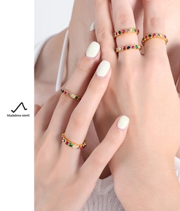 Detailed close-up of stacked gold-plated stainless steel rings with colorful zircon stones