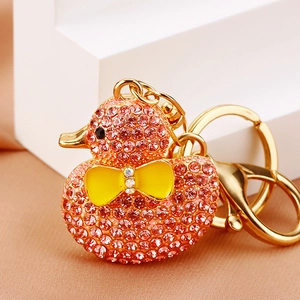 Close-up of pink rhinestone duck keychain with gold metal bow on a silk pedestal