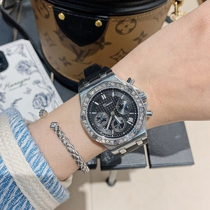 Detail of a luxury chronograph watch with diamond bezel and black silicone strap on wrist
