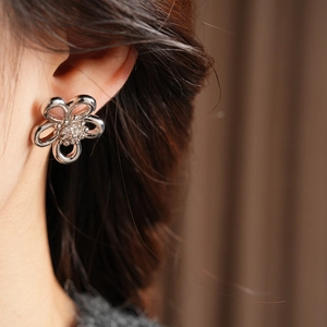 Macro view of silver-tone hollow flower stud earring with sparkling crystal center
