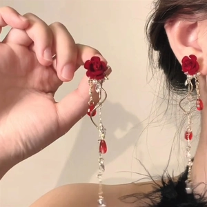 Detail of elegant red floral tassel earrings with gold chain and teardrop crystals