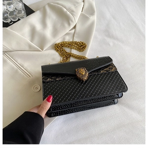 Detail of black crocodile texture bag with gold lion head hardware on white blazer