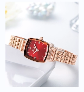 Detail of rose gold square watch with red dial and rhinestone markers on white ceramic