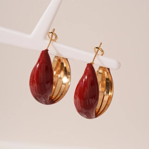 Close-up of vintage deep red enamel teardrop hoop earrings with polished gold lining