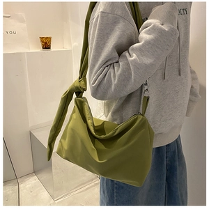 Detail of green nylon crossbody bag showing knotted adjustable strap and metal chain
