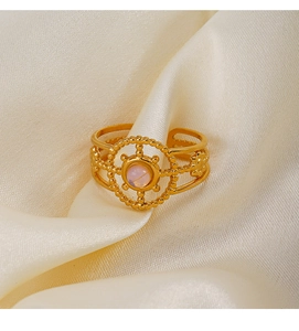 Close-up of a gold stainless steel ring featuring a round pink gemstone on silk fabric