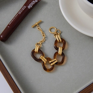 Detail of vintage 18K gold stainless steel chain bracelet with amber resin oval rings