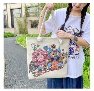 Detailed outdoor shot of canvas tote bag with owl floral embroidery and rope handles