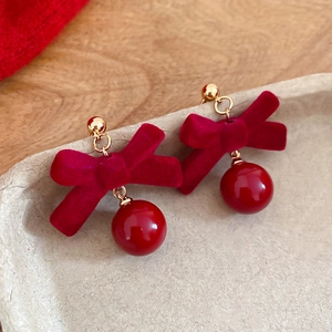 Détail de boucles d'oreilles nœud rouge floqué avec perles brillantes et métal doré