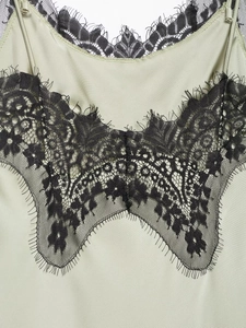 Detail of sage green satin dress with exquisite black eyelash lace trim and V-neckline
