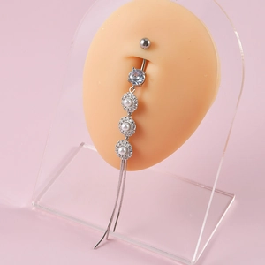 Macro detail of silver tassel belly ring with zircon and pearls on a silicone navel model