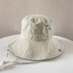 Détail d'un chapeau de soleil beige en nylon avec cordon et évents métalliques sur bois