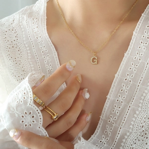 Elegante Halskette aus Gold-Titanstahl mit Zirkon-G-Anhänger und goldenen Ringen