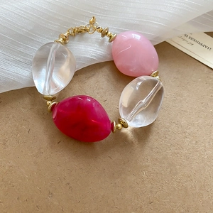 Detailed macro view of acrylic oval beaded bracelet with lobster clasp and gold spacers