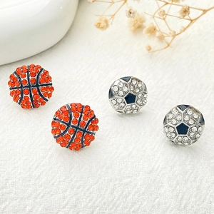 Gros plan de boucles d'oreilles clous de basket et football avec strass sur tissu blanc