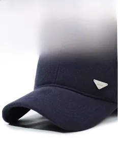 Detail of navy wool baseball cap showing firm brim and metallic triangle emblem
