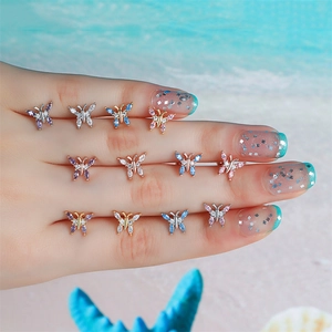 Detailed display of colorful zircon butterfly stud earrings on a hand with beach theme