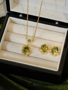 Detailed macro of 18K gold plated jewelry set with oval green emeralds and white zircons
