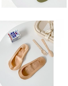 Detail of skin-toned low cut liner socks made of breathable soft fabric on a white surface
