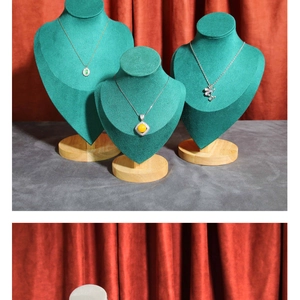 Green velvet necklace bust display stand with wooden base on deep red backdrop