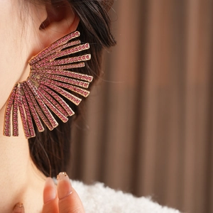 Detail of fan-shaped gold earrings with pink and purple rhinestones on a model