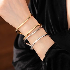 Détail de bracelets joncs doubles irréguliers superposés en finitions or et argent