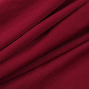 Close-up of wine red fabric texture showing soft pleats and smooth textile draping