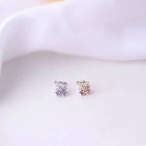 Detail of L-shaped nose studs with silver and gold butterfly design and purple crystals