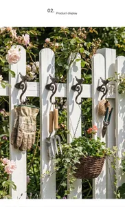 Ganchos de pared de pájaros de hierro fundido vintage en valla blanca con flores de jardín