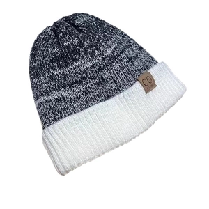 Winter knit beanie featuring black and white patchwork design and a brown leather logo patch