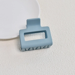 Detail of light blue matte square hair claw clip with hollow design on white background