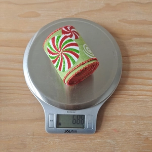Detailansicht eines grünen Weihnachtsbandes mit Zuckerstangen-Druck auf einer Waage