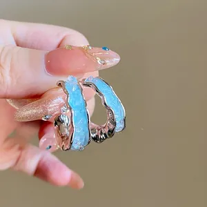 Vue macro détaillée des boucles d'oreilles C en argent S925 avec bords ondulés bleus