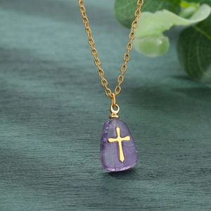 Detailed macro view of purple natural stone cross pendant with golden stainless steel chain