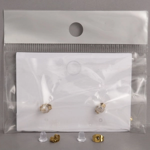 Macro shot of gold-plated butterfly earring backs and transparent silicone stoppers on card