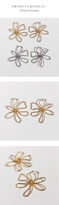 Detailed view of large gold and silver hollow metal flower earrings in wire design