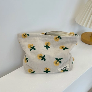 Détail de la broderie florale et de l'étiquette Sozakka sur la trousse en toile crème