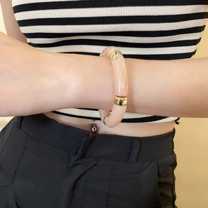 Close-up of pink iridescent acrylic geometric bracelet with gold metal spacer rings