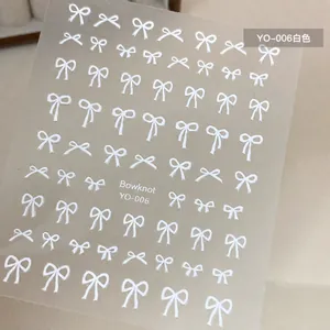 Close-up of white bowknot nail art stickers YO-006 on minimalist beige background