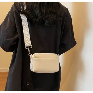 Detail of beige PU leather crossbody bag with golden zipper and wide woven strap