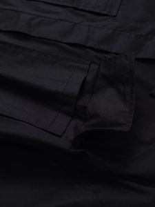 Detailed macro view of black cargo shirt pocket with reinforced stitching and fabric texture