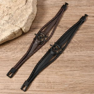 Vintage braided leather bracelets with black metal anchor charm on wood background